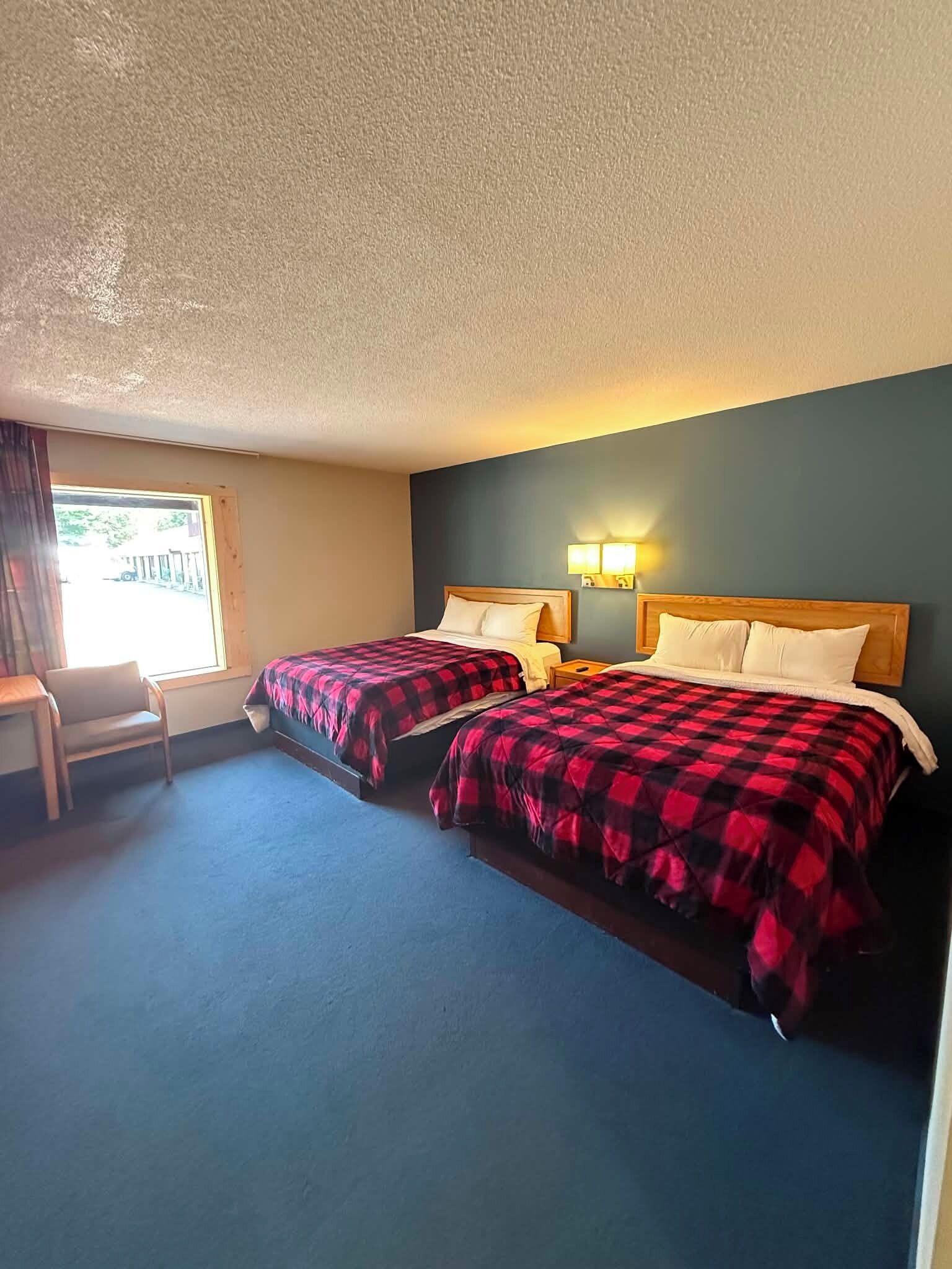 Habitación de hotel con dos camas, una silla y una ventana.