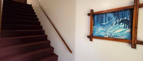 Una escalera con barandilla de madera y un cuadro de un lobo en la pared.