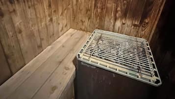 A wooden cabin interior with a bench and a metal storage unit.