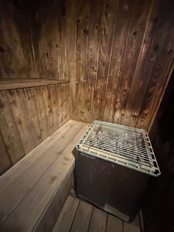 A wooden cabin interior with a bench and a metal storage unit.