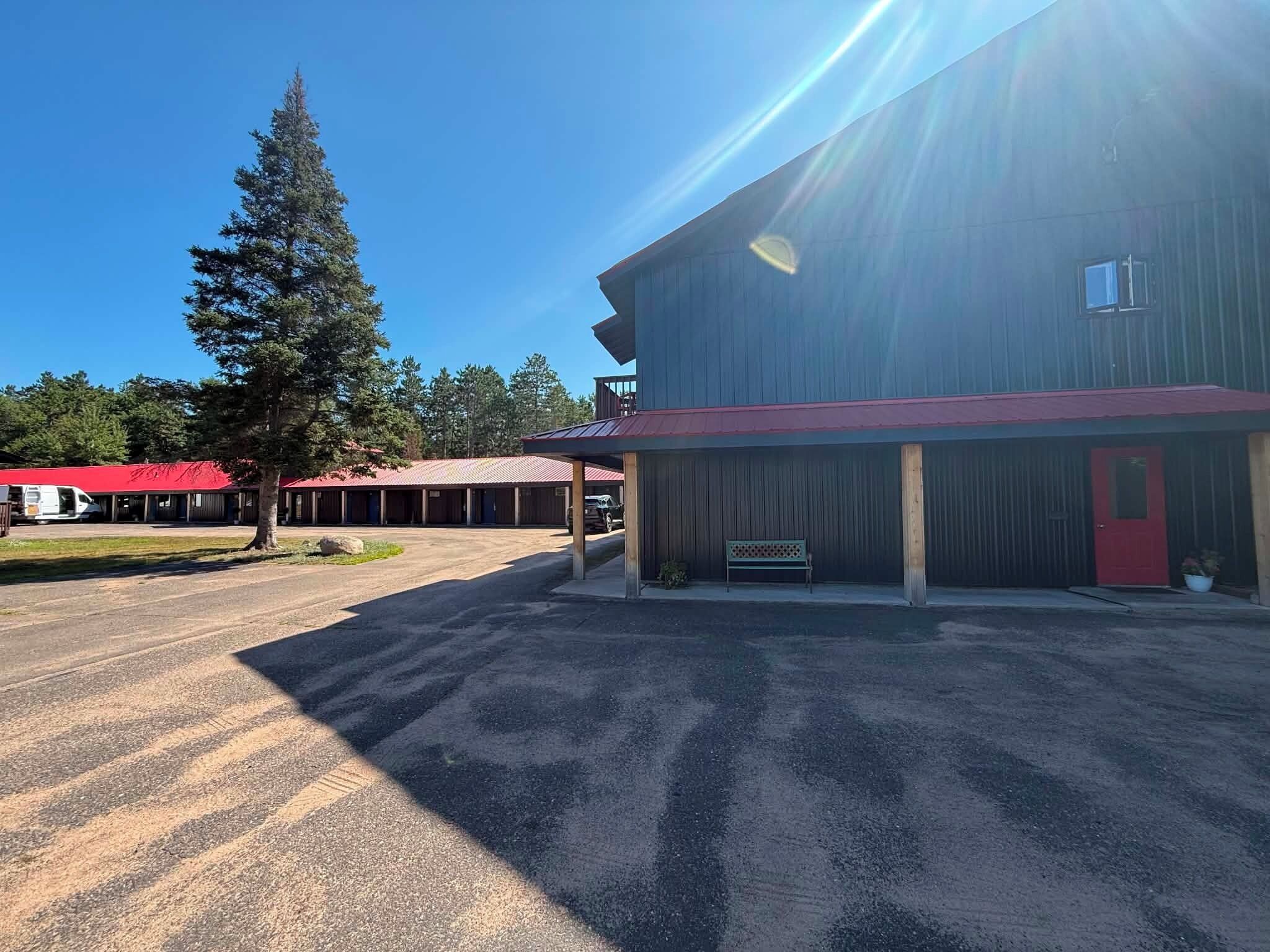 A building with a red door and a covered parking area.