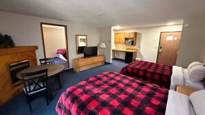 A hotel room with two beds, a desk, a television, a microwave, and a small kitchenette. - Northwestern Lodge (Hayward)