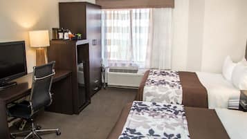 Une chambre d’hôtel équipée d’un bureau, d’une chaise, d’une télévision, d’un système de climatisation et de deux lits.