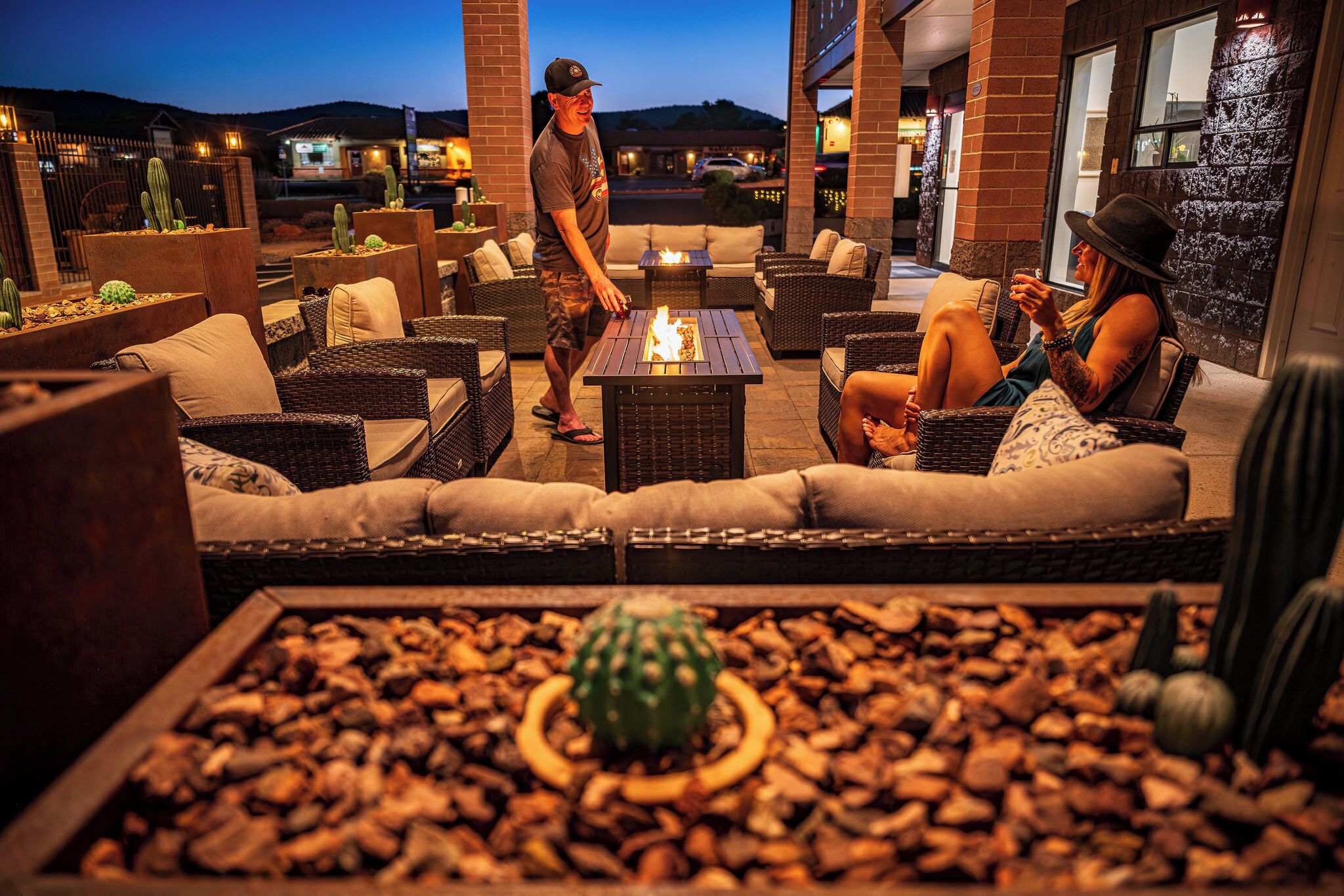 An outdoor seating area with wicker furniture, a fire feature, and cacti.