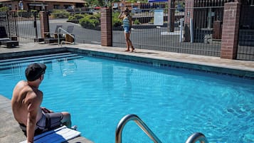 Una piscina con barandillas metálicas, una toalla en el borde y una persona sentada sobre otra toalla.
