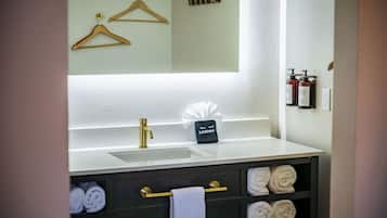 Un baño con lavamanos, toalleros, espejo y neceser.