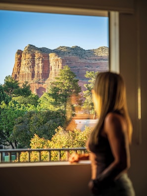 A room with a large window overlooking a canyon with red rock formations and green trees.