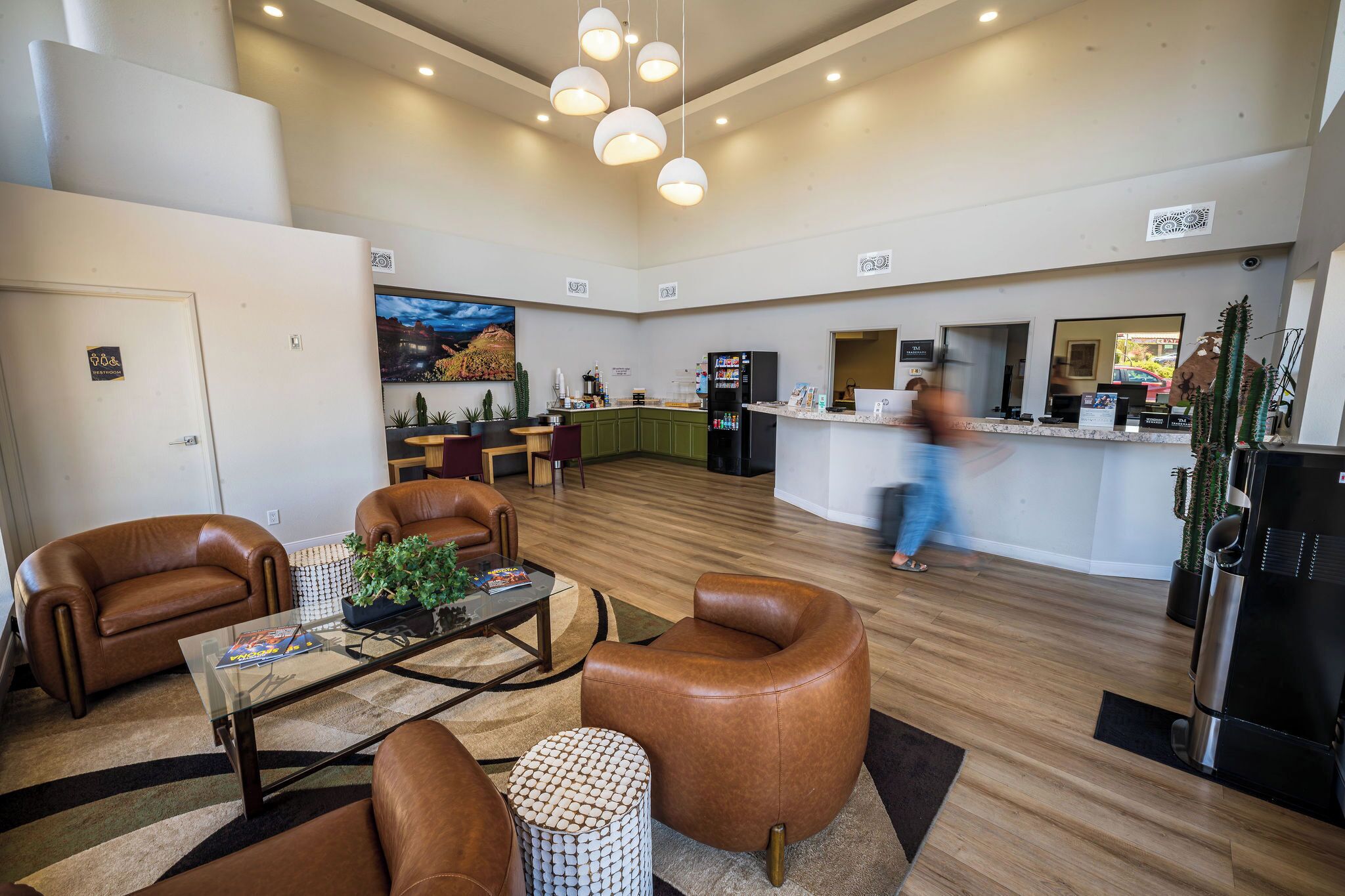 A modern hotel lobby with leather sofas, a coffee table, a kitchen area, and a bar.