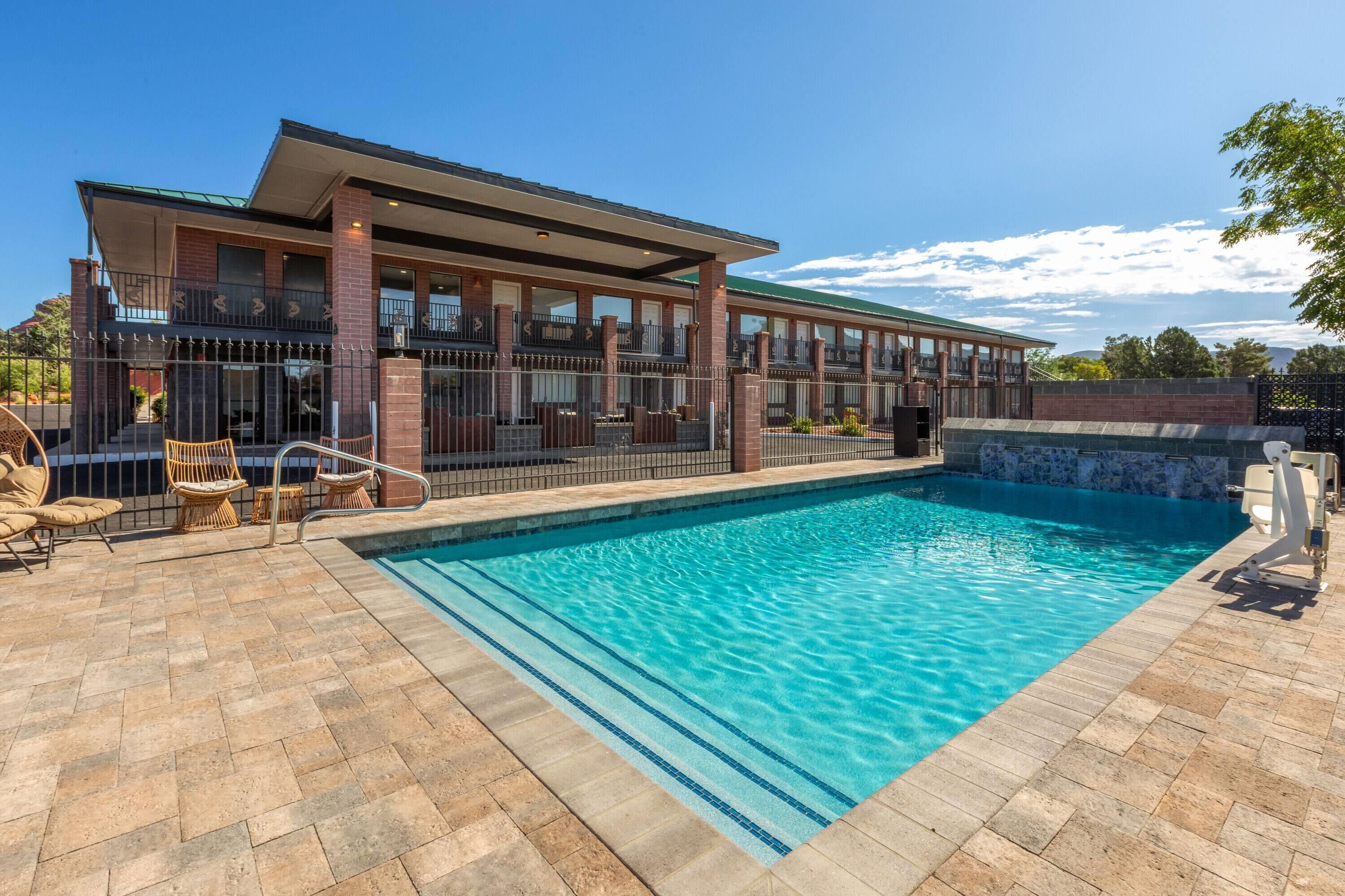 A hotel with a swimming pool, outdoor seating, and a covered area.