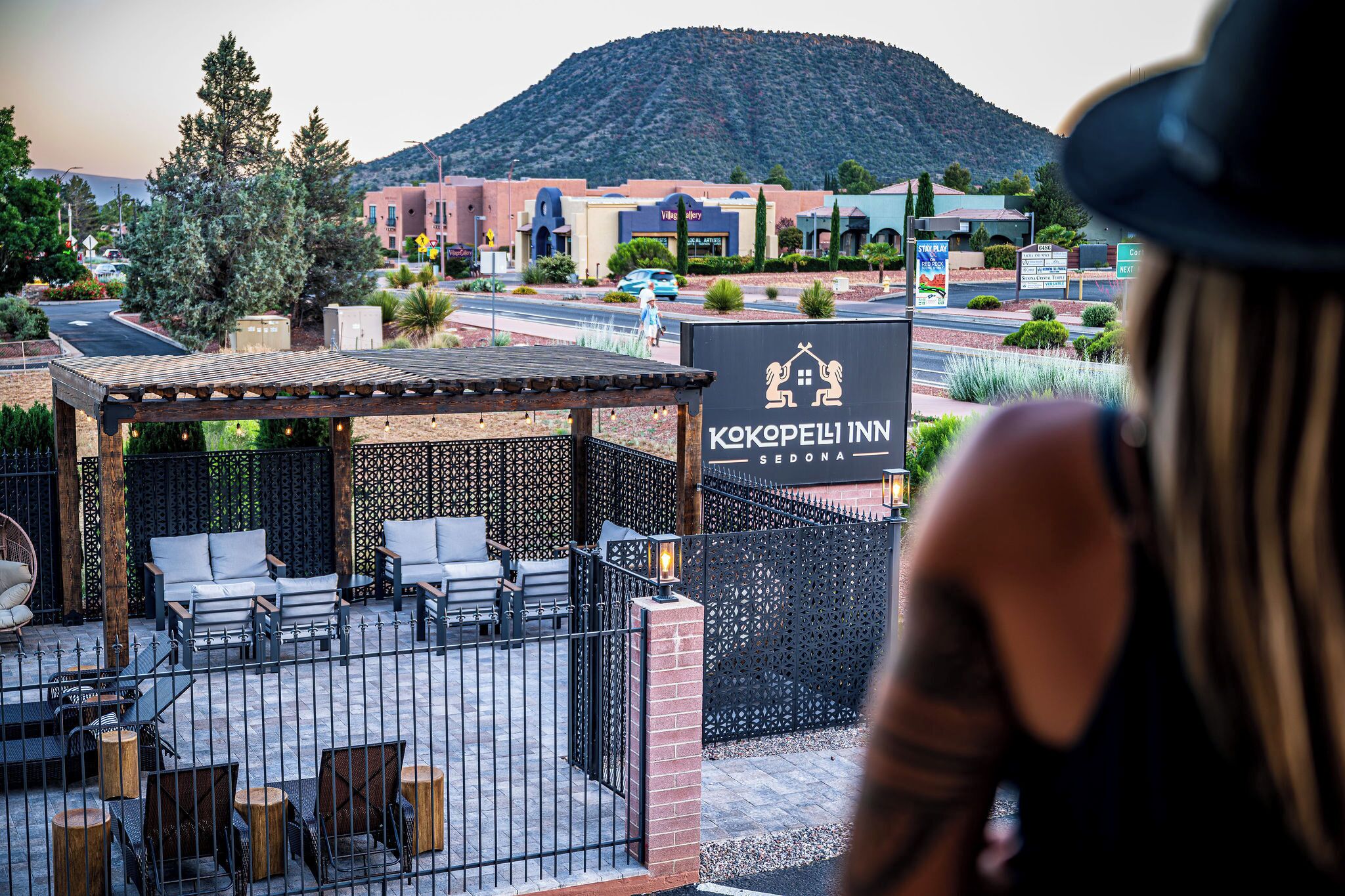 A fenced outdoor seating area with chairs and tables, a sign for Kokopelli Inn, and a mountain in the background.