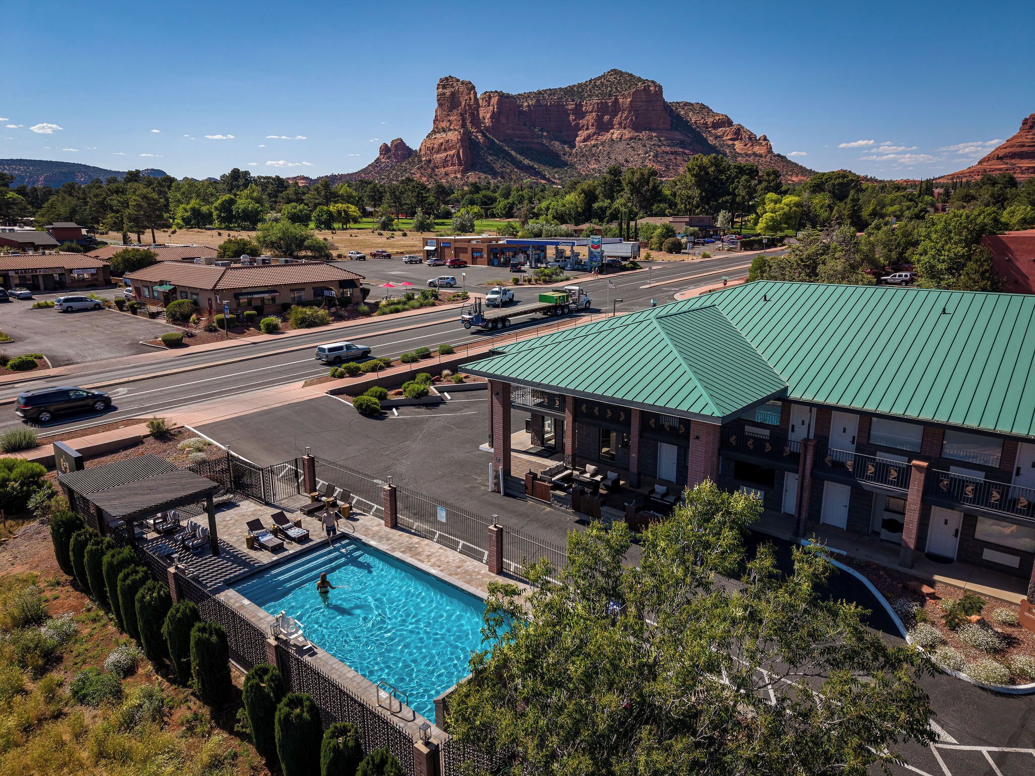 A hotel with a swimming pool, a parking lot, and a mountain in the background.