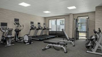 Ein Fitnessstudio mit Laufbändern, Crosstrainern und Gewichtbänken.