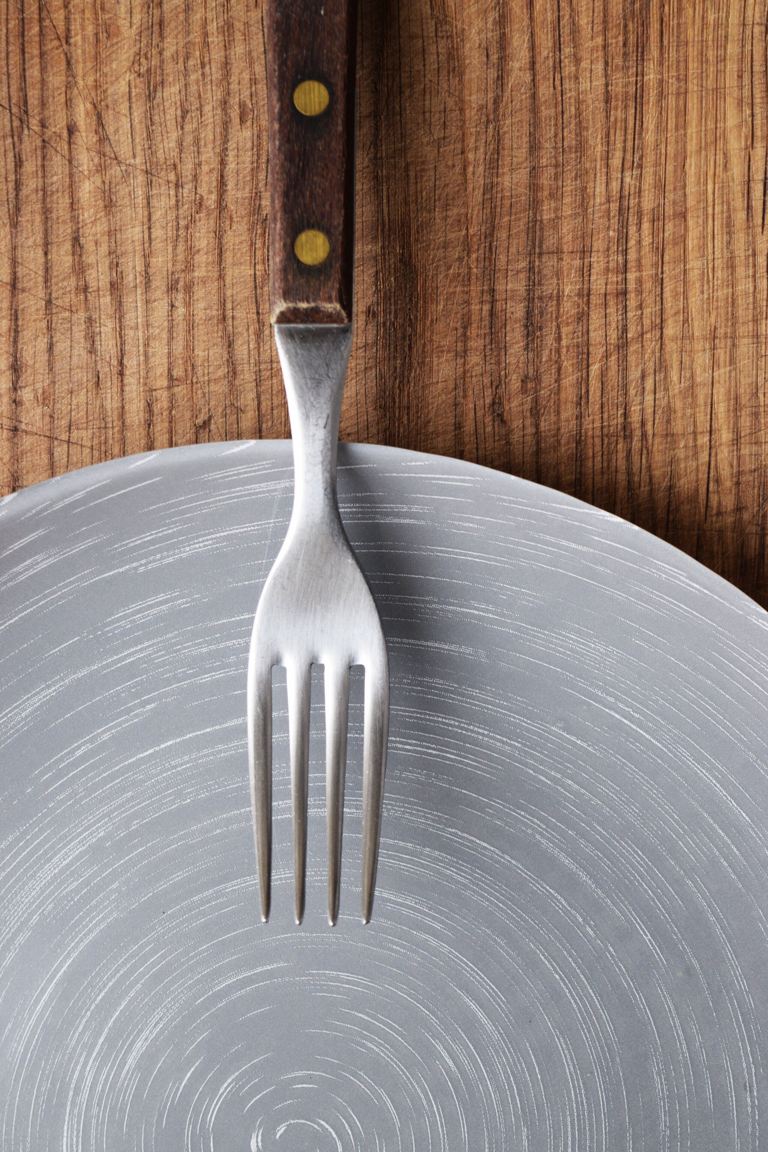 A fork on a gray plate with a wooden background.