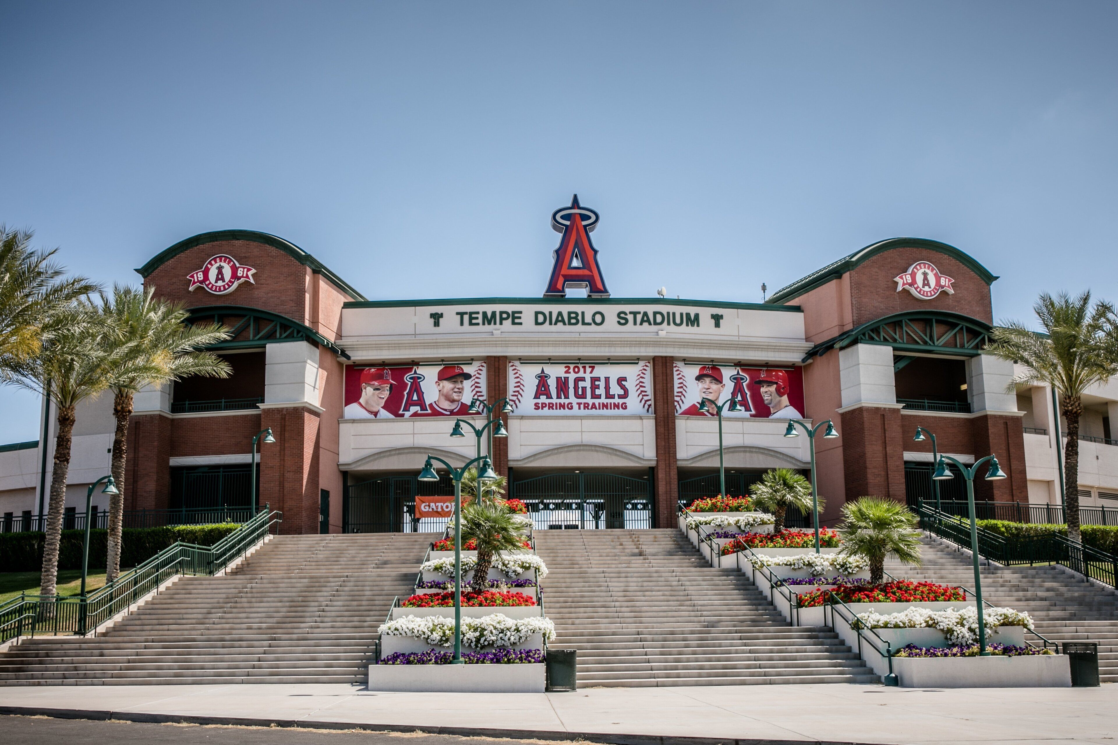 La entrada al Estadio Tempe Diablo con escaleras que conducen a la entrada principal, palmeras y un gran cartel de entrenamiento primaveral de los Angels.