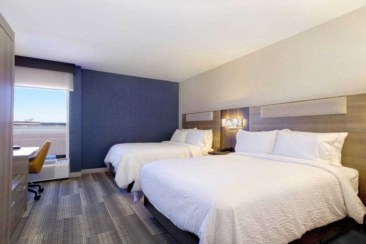 Une chambre d’hôtel avec deux lits, un bureau et une chaise.