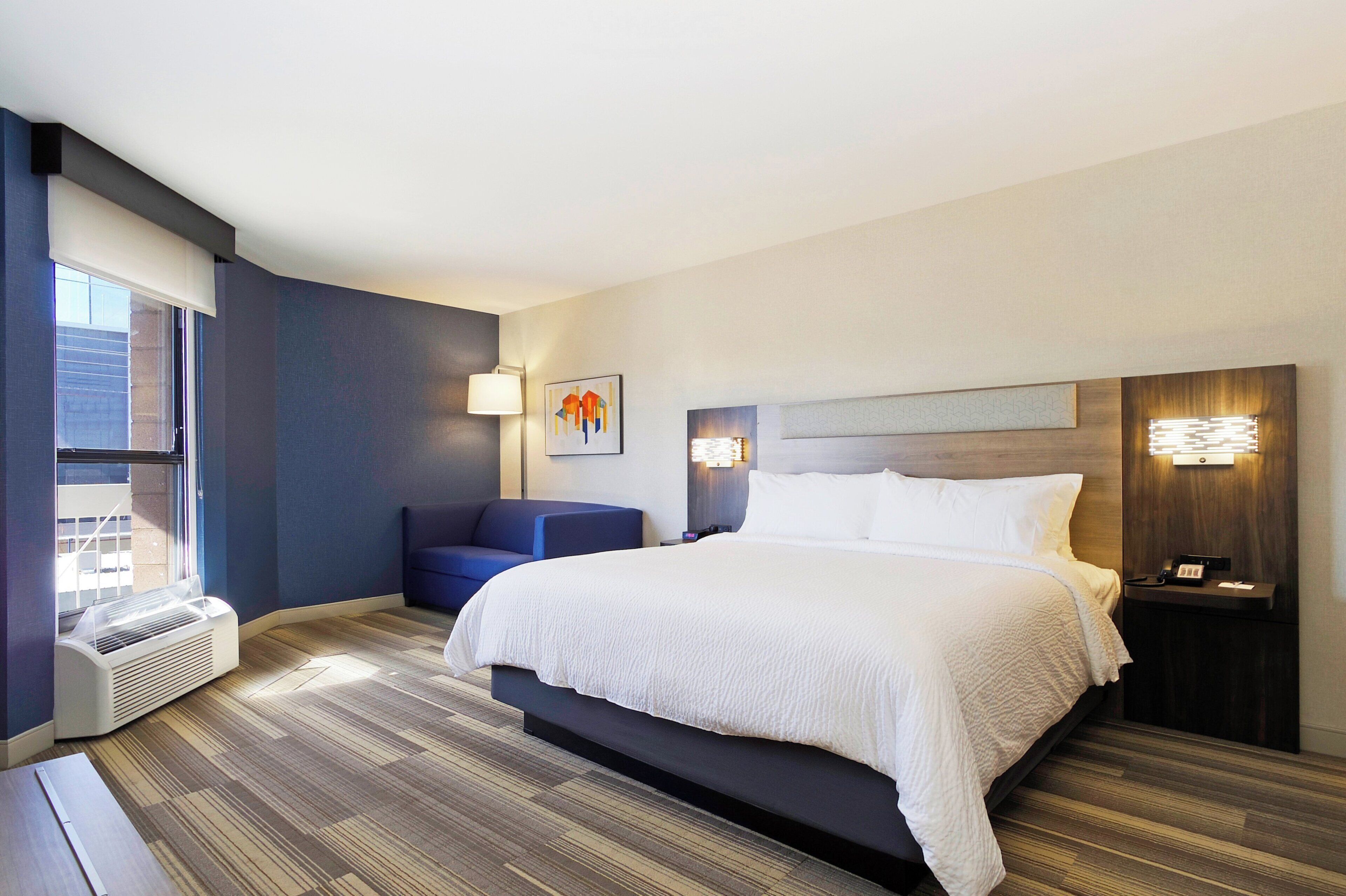 Una habitación de hotel con una cama grande, una zona de estar y un escritorio con lámpara.