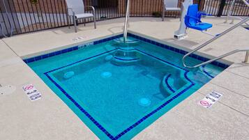 A swimming pool with a blue tiled border, a diving board, and two lounge chairs.