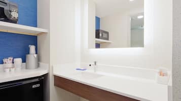 Un baño con un lavamanos blanco, un espejo y un toallero azul.