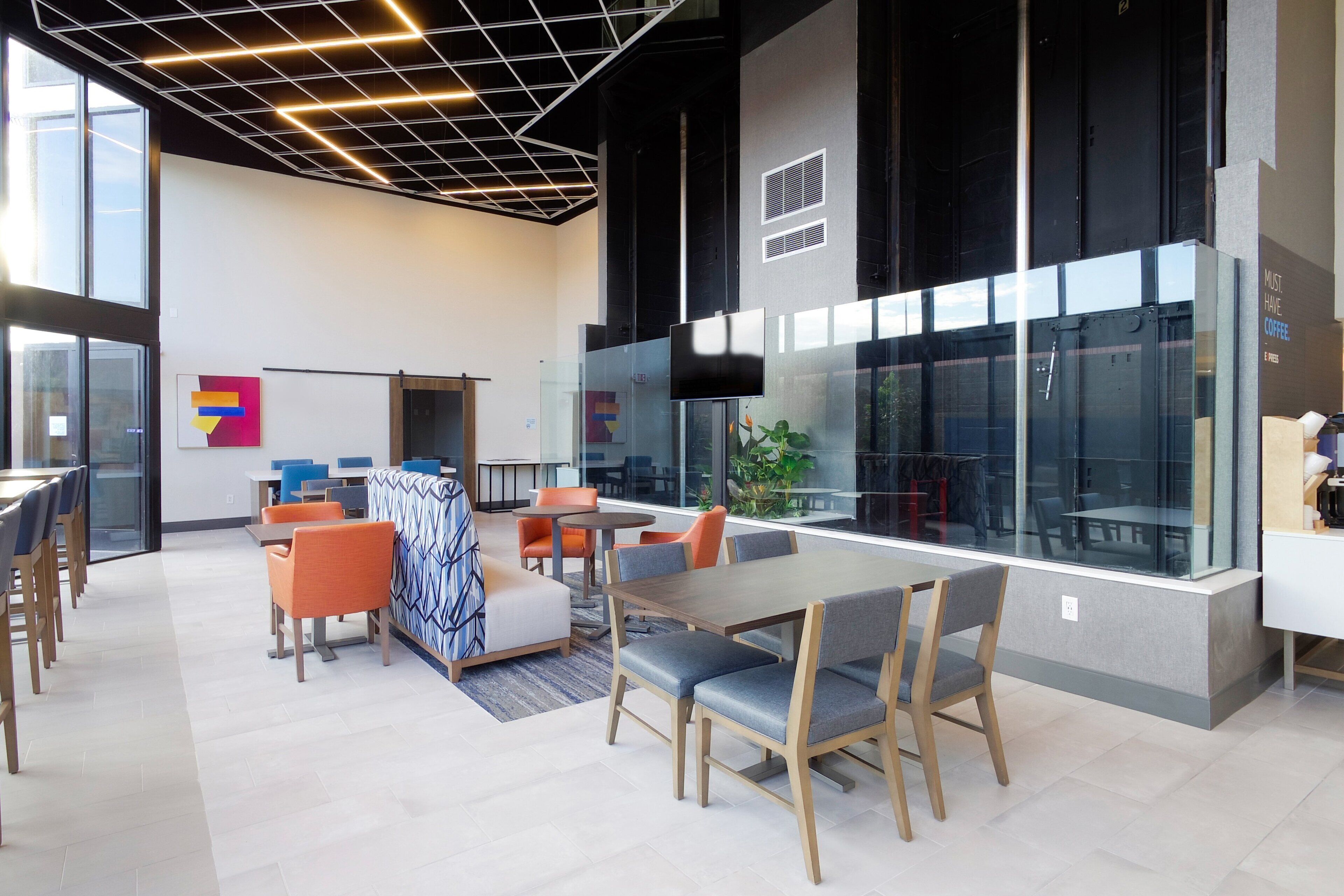 A modern office space with a large meeting table, comfortable seating, and large windows.