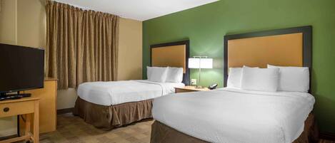 A hotel room with two beds, a television, a desk, and a lamp.