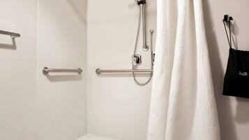 A walk-in shower with a white curtain, grab bars, and a handheld showerhead.