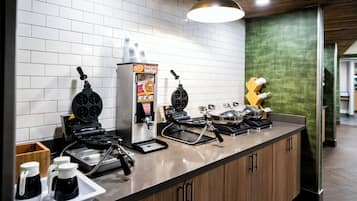 Un plan de travail de cuisine avec des appareils à gaufres, une machine à café et un gaufrier.