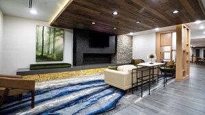 A modern living room with a fireplace, a large painting, and a dining area. - Fairfield Inn & Suites by Marriott Louisville Airport (Louisville)