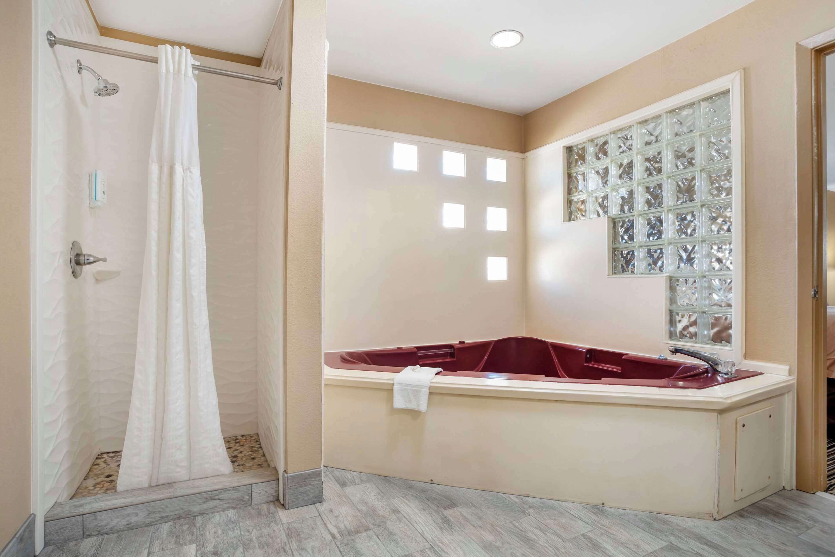Un baño con ducha, bañera y ventana con paneles de vidrio decorativos.