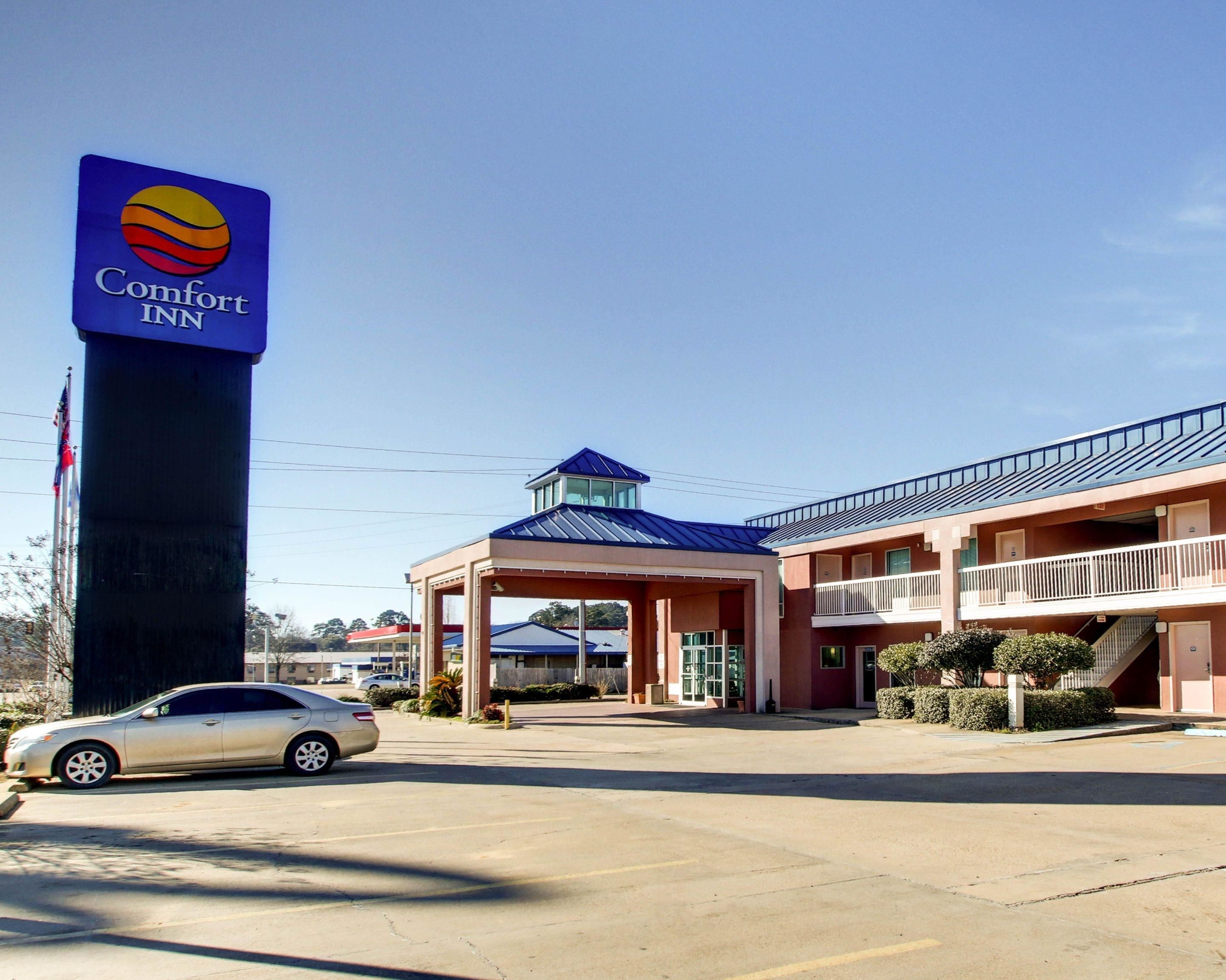 Un hotel Comfort Inn con un letrero llamativo, una entrada cubierta y un estacionamiento con un automóvil.