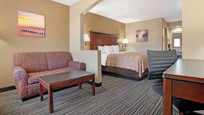 A hotel room with a sofa, bed, desk, and chair. - Quality Inn Brookhaven (Brookhaven)