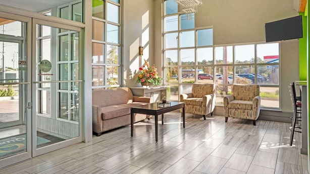 A spacious room with large windows, a sofa, two armchairs, a coffee table, and a chandelier. - Quality Inn Brookhaven (Brookhaven)