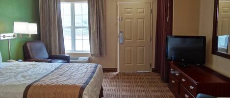 A hotel room with a bed, a television, a desk, and a chair.