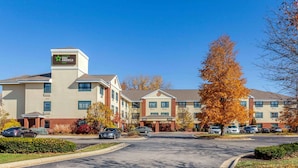 A Holiday Inn Express hotel with a central entrance, multiple parking spaces, and autumn foliage.
