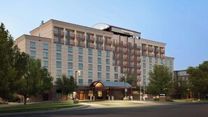 A multi-story hotel with a prominent 'Courtyard' sign, featuring a brick facade, multiple balconies, and a well-lit entrance. - Courtyard by Marriott Denver Airport (Denver)