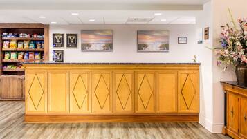 A reception area with a wooden counter, framed awards, and a flower arrangement.