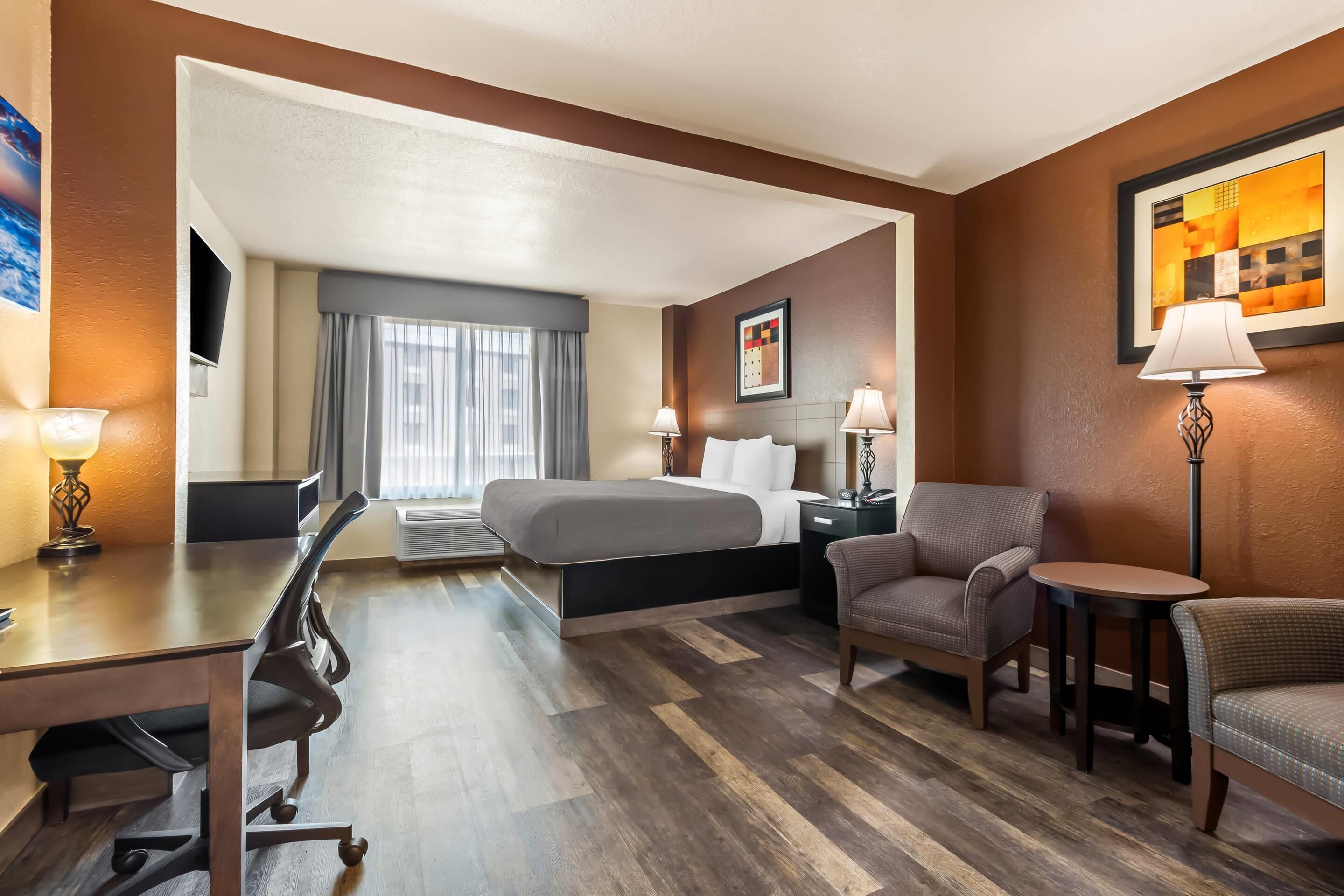 Een hotelkamer met een bed, bureau, stoelen en een klein tafeltje.