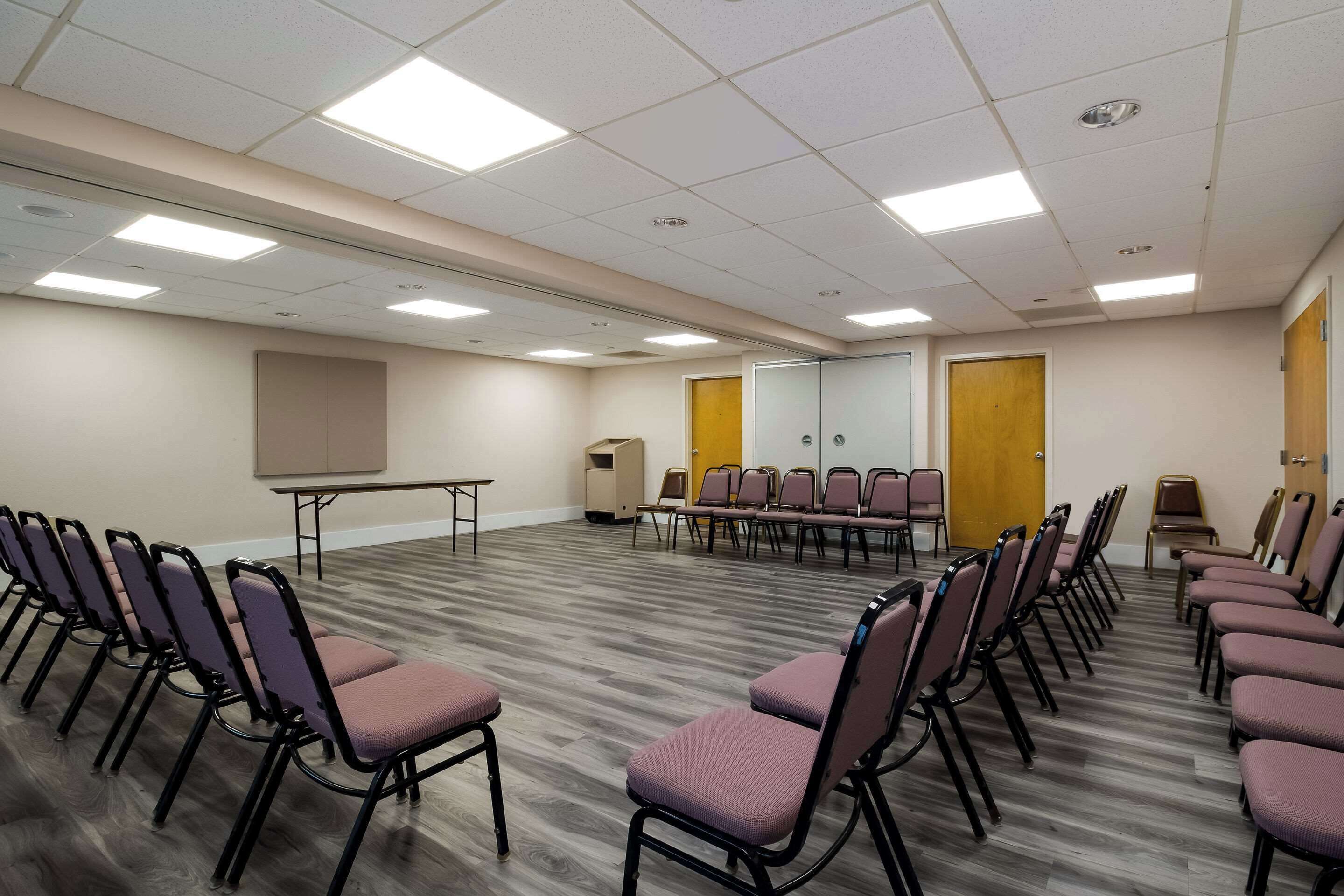 A conference room with rows of chairs, a projector screen, and a podium.
