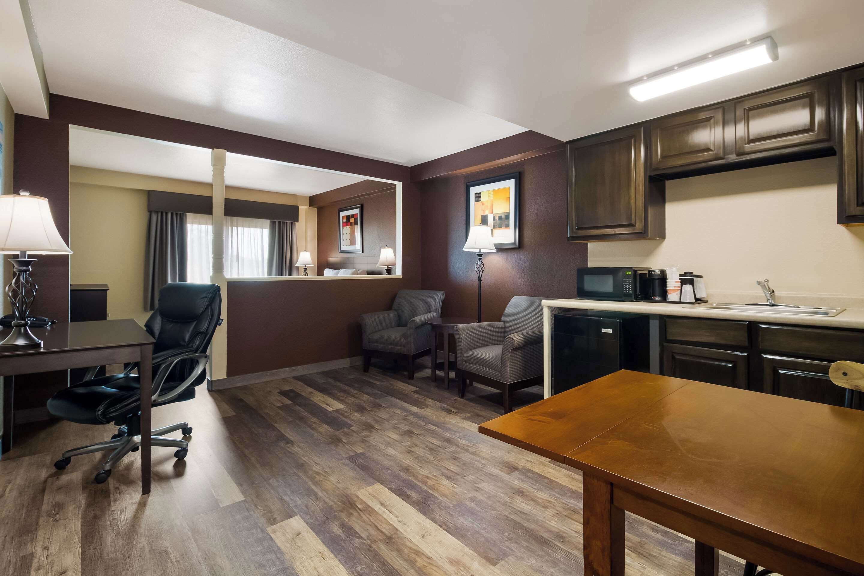 Une chambre d’hôtel compacte comprenant un coin cuisine, un espace repas et un coin salon avec deux chaises.