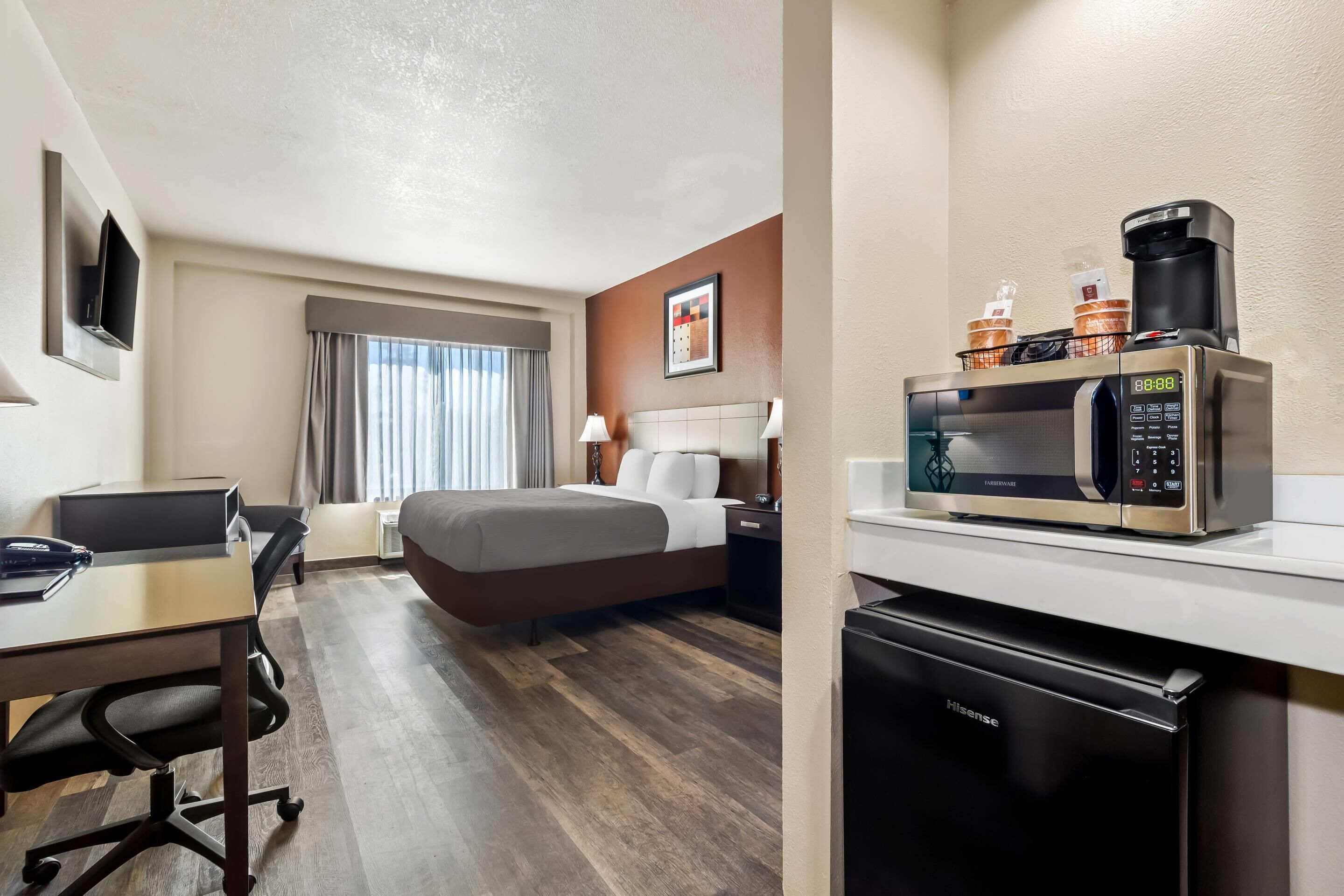 Une chambre d’hôtel avec un lit, un bureau et une kitchenette.