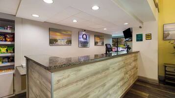 A hotel reception area with a marble counter, a 'Quality' sign, and a 'By Choice Hotels' logo.