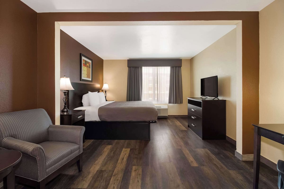 A hotel room with a bed, a desk, a chair, a television, and a window with curtains.