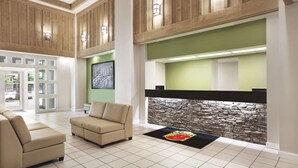 A lobby with a stone wall, beige sofas, and a reception desk. - Super 8 by Wyndham Cherokee (Cherokee)