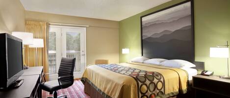 A hotel room with a bed, a desk with a computer, a chair, a TV, and a window with curtains.