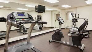 A fitness center with treadmills, an elliptical, and a TV screen. - Super 8 by Wyndham Cherokee (Cherokee)