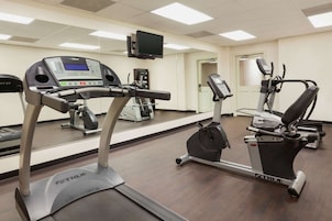 Un gimnasio con cintas de correr, elíptica y una pantalla de televisión.