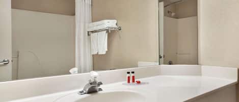 A modern bathroom with a large mirror, a white sink, and a shower area.