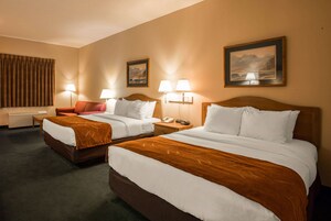 Habitación de hotel con dos camas, un sofá y dos lámparas.