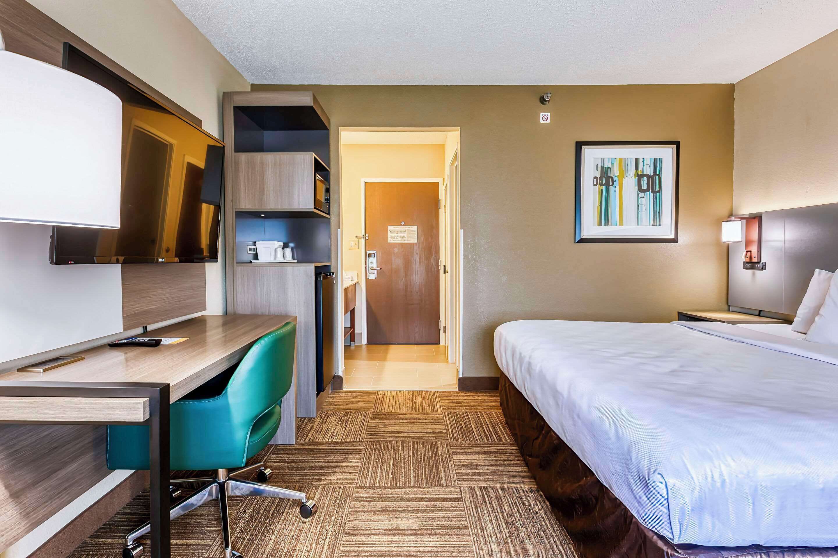 Ein Hotelzimmer mit Bett, Schreibtisch, Stuhl und Fernseher.
