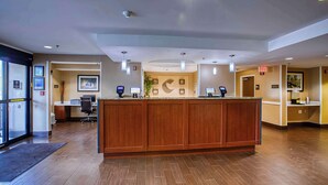 A reception area with a wooden reception desk, a computer station, and a large window. - Comfort Inn Shepherdsville - Louisville South (Louisville)
