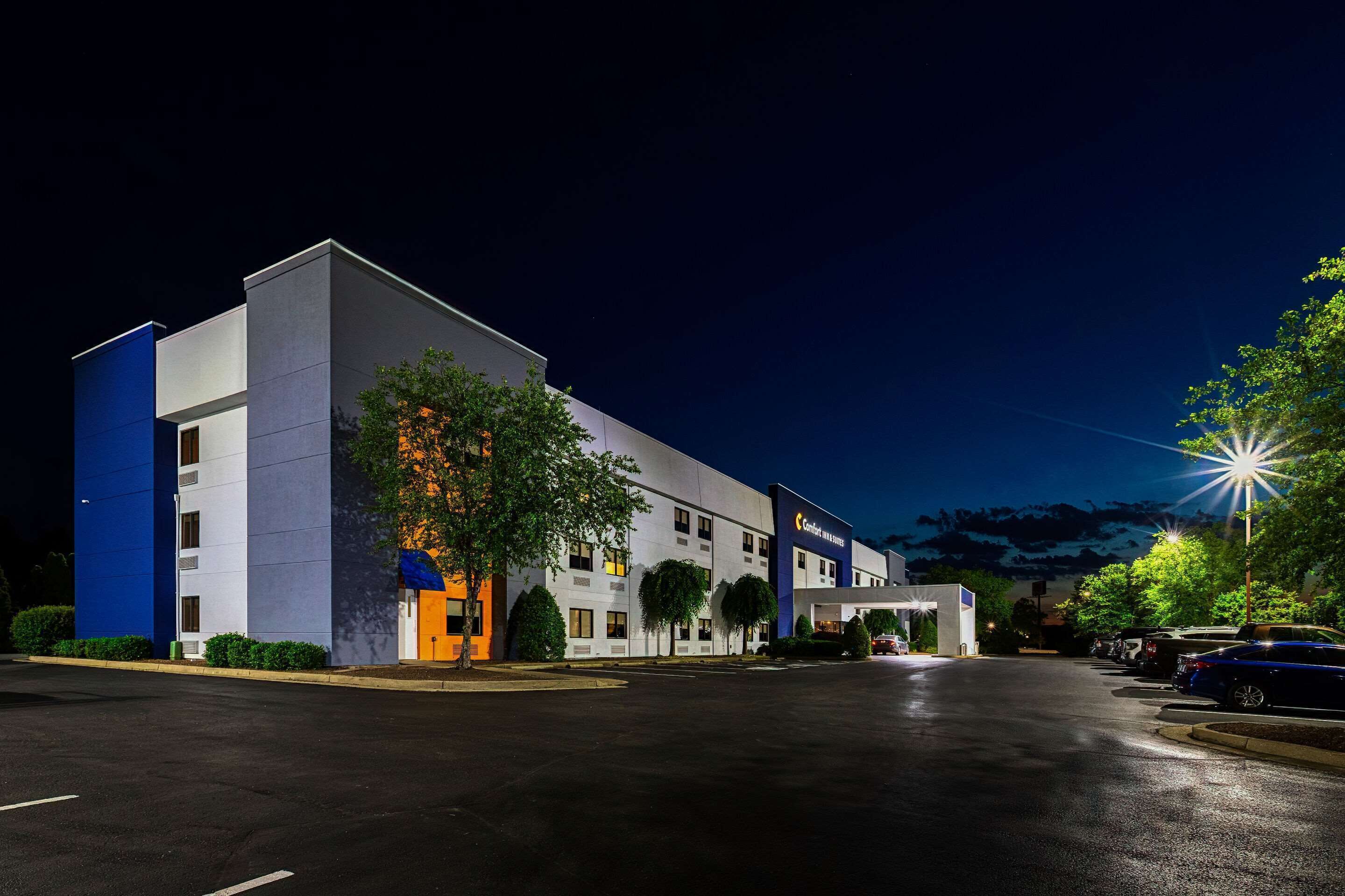 A modern hotel with a flat facade, multiple windows, and a parking lot.